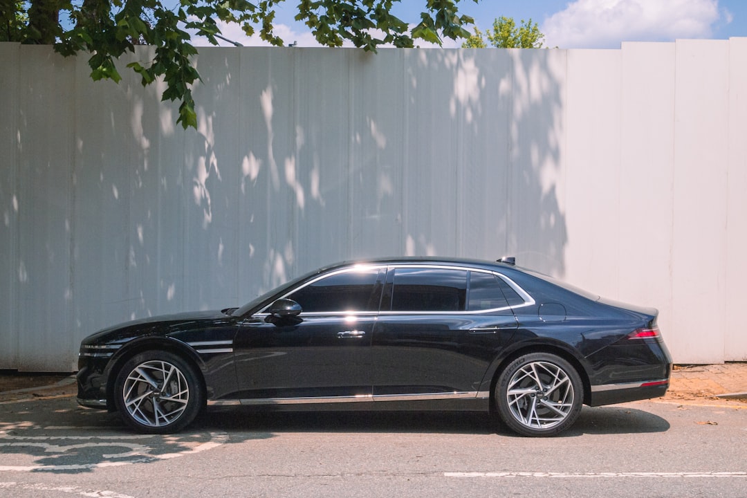 A sleek black sedan parked against a white wall.