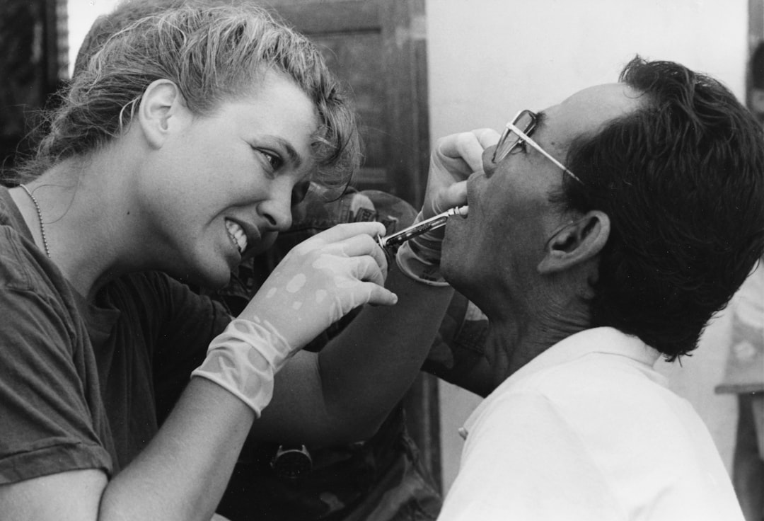 Dentist examines patient's teeth with tools.