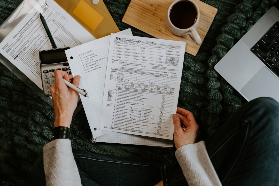 Person reviewing documents with calculator and laptop.