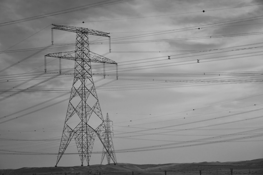 Tall power lines and pylons under a cloudy sky.